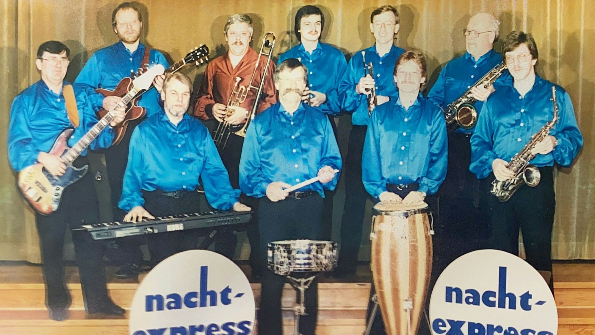 Eine Tanzkapelle posiert mit elektrischen Instrumenten.