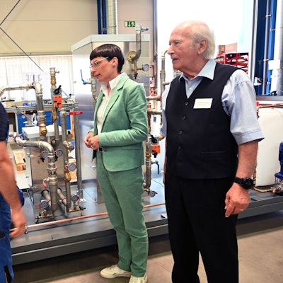 Vor einer Maschine stehen Ministerin Josefine, ONI-Chef Wolfgang Oehm und sein Mitarbeiter Hussein Zeider