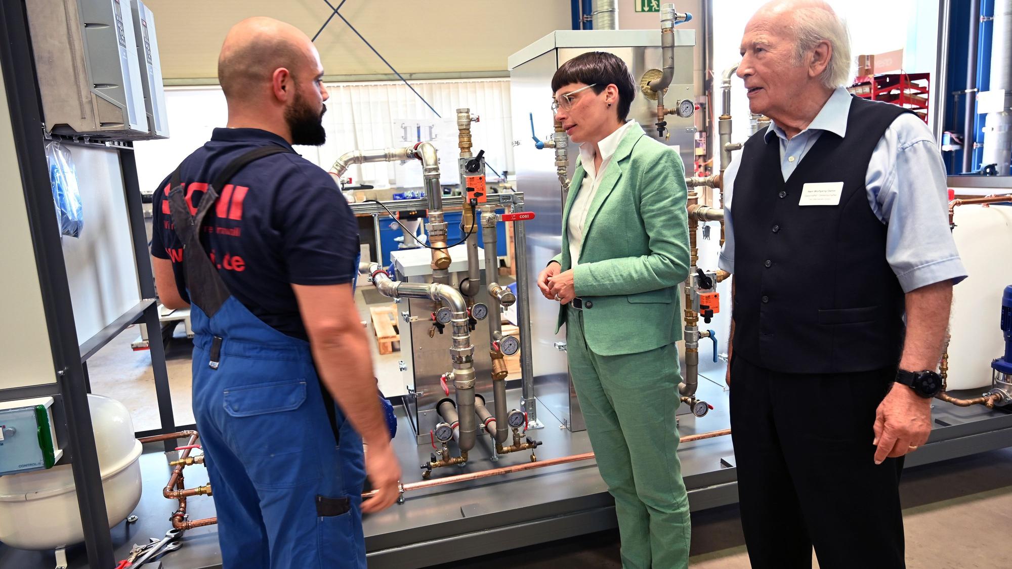 Vor einer Maschine stehen Ministerin Josefine, ONI-Chef Wolfgang Oehm und sein Mitarbeiter Hussein Zeider