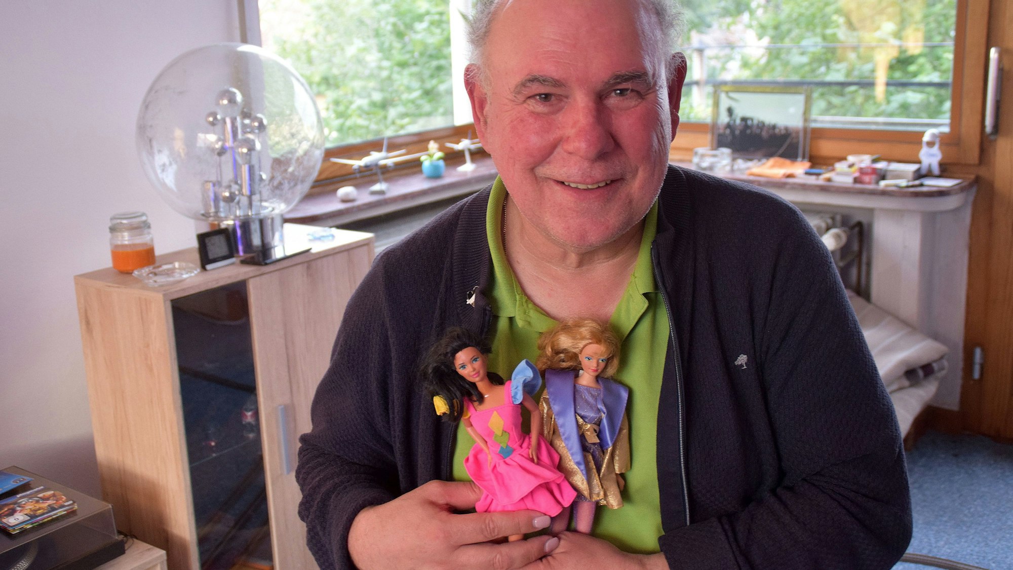 Karl-Heinz Nauroth hält zwei Barbiepuppen in der Hand.