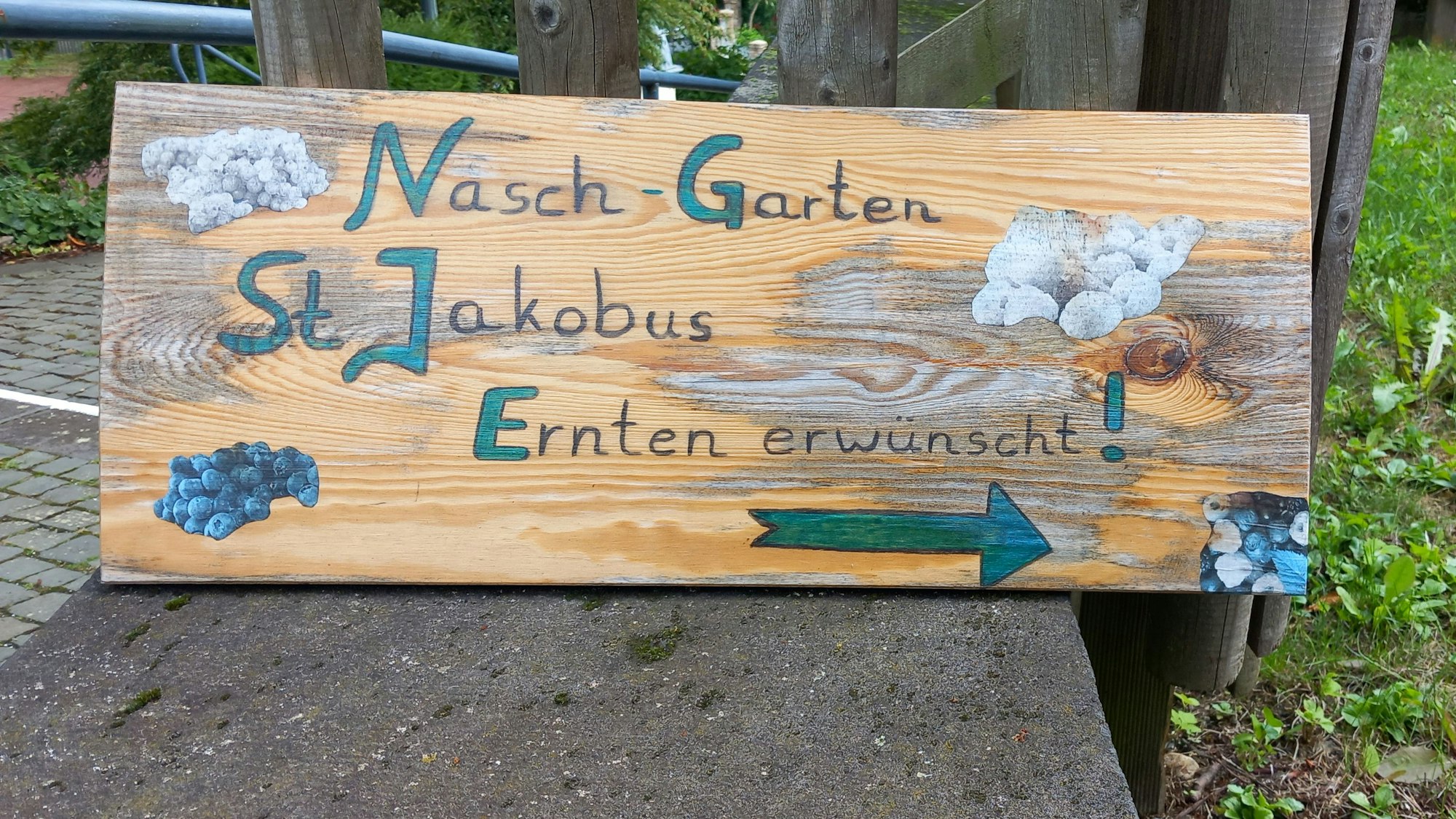 Auf einem Holzschild ist zu lesen "Nasch-Garten St. Jakobus Ernten erwünscht"