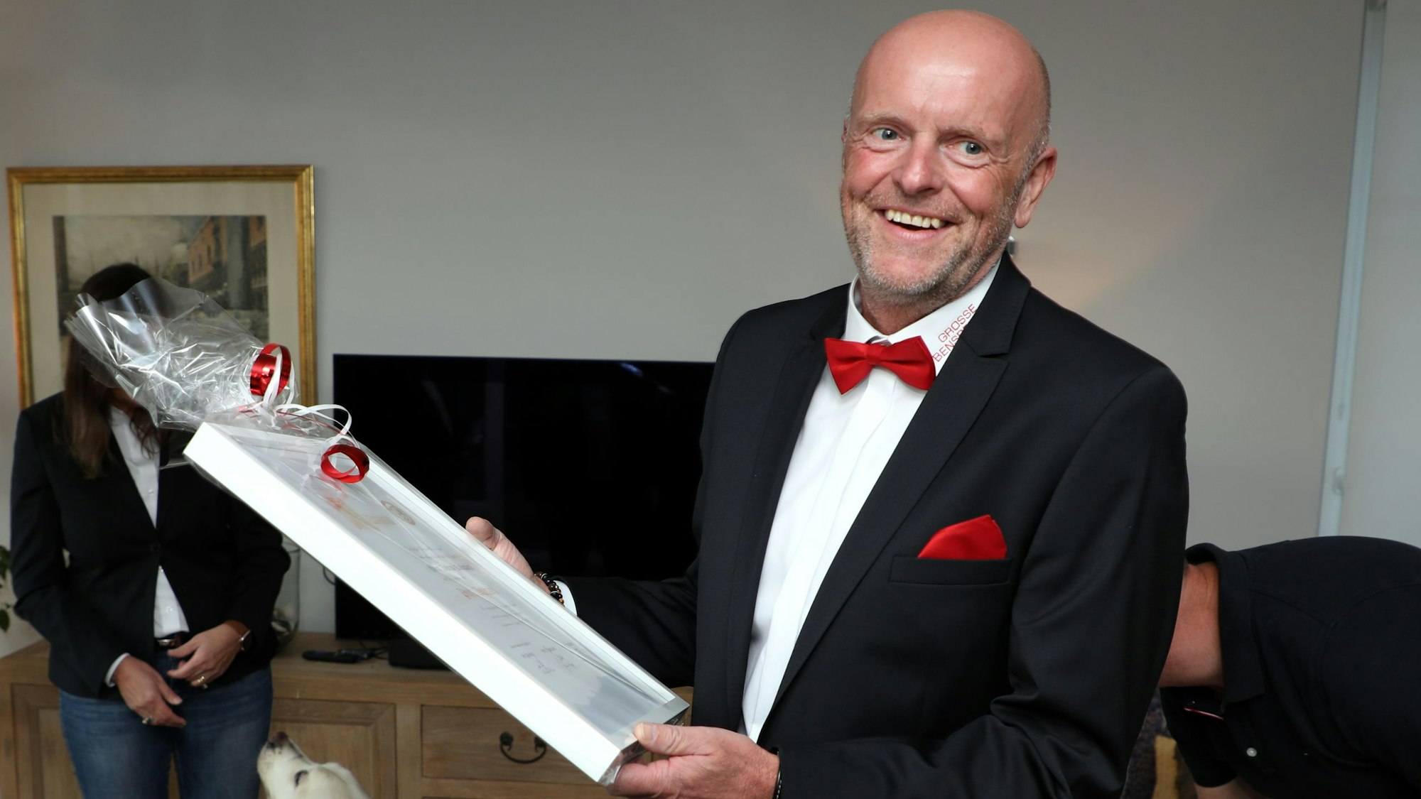 Ein Mann hält eine in Folie gefasste Urkunde in Händen.