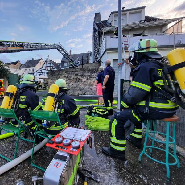 Feuerwehrleute, die Atemschutzgeräte tragen, beobachten den Einsatz der Drehleiter der Feuerwehr.
