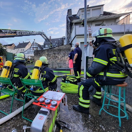 Feuerwehrleute, die Atemschutzgeräte tragen, beobachten den Einsatz der Drehleiter der Feuerwehr.