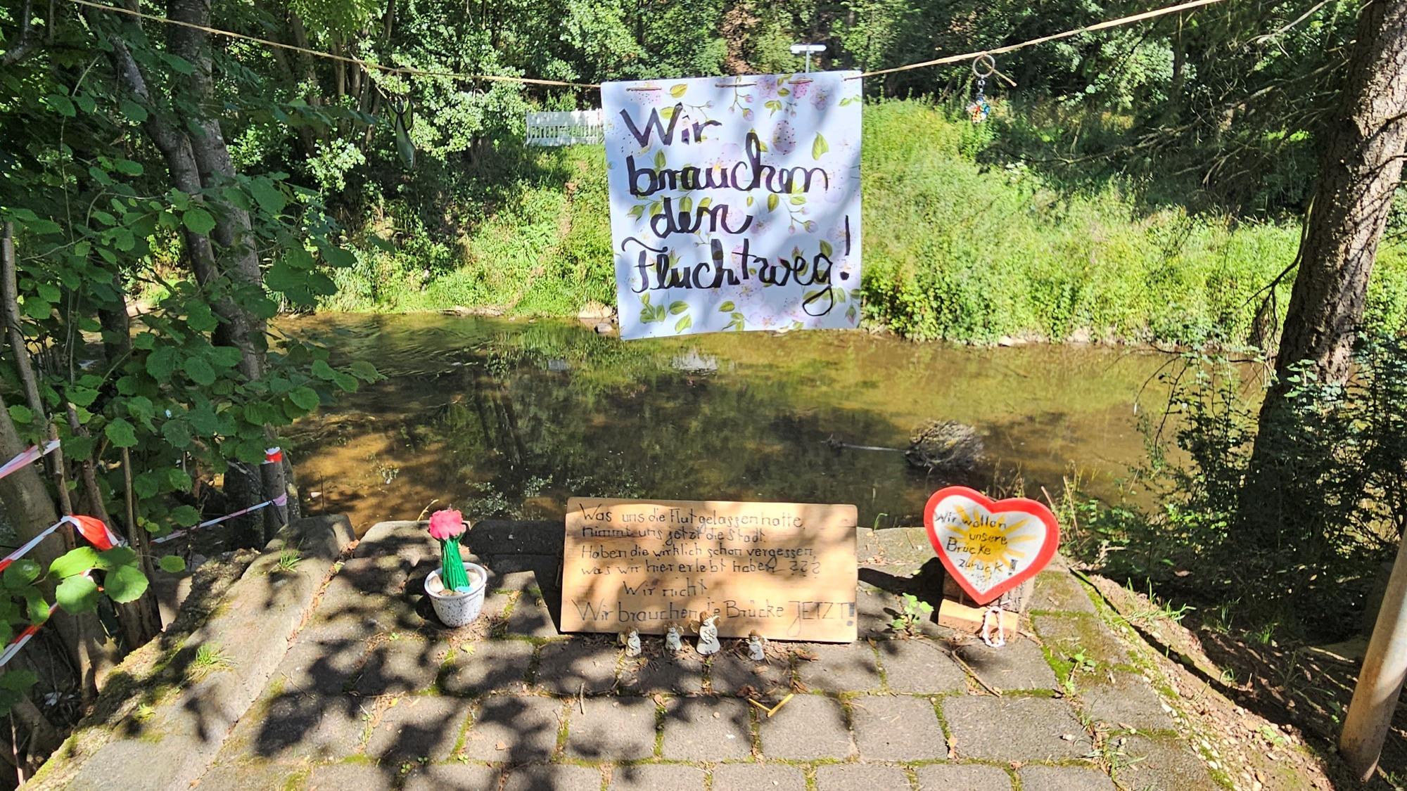 Auf dem Aufgang zur abgerissenen Brücke in Mauel hängt an einer Kordel ein Schild der Anwohner mit der Aufschrift „Wir brauchen den Fluchtweg“.