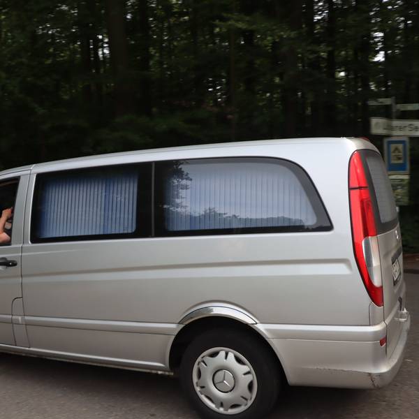 Ein Leichenwagen an der Zufahrt zu einem Waldstück.