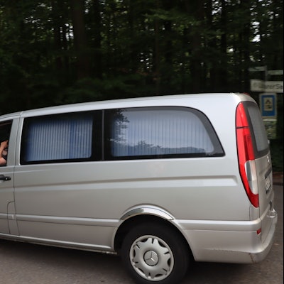 Ein Leichenwagen an der Zufahrt zu einem Waldstück.