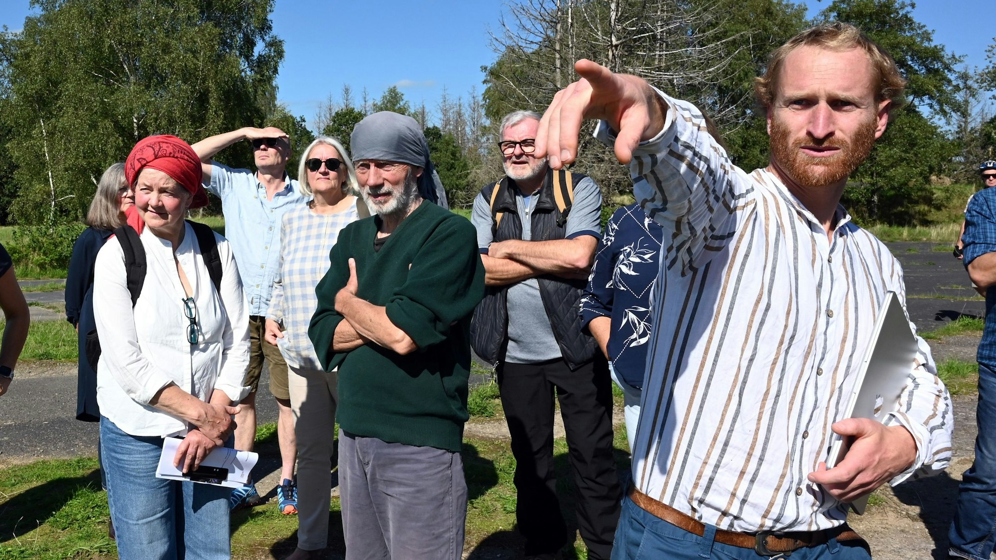 Johannes Thema von der „Wind in der Nutscheid“ (rechts) zeigt Interessierten und Waldbröler Politikerinnen und Politik am Hohen Wäldchen, wo auf dem Nutscheid-Höhenzug die Windräder platziert werden könnten.