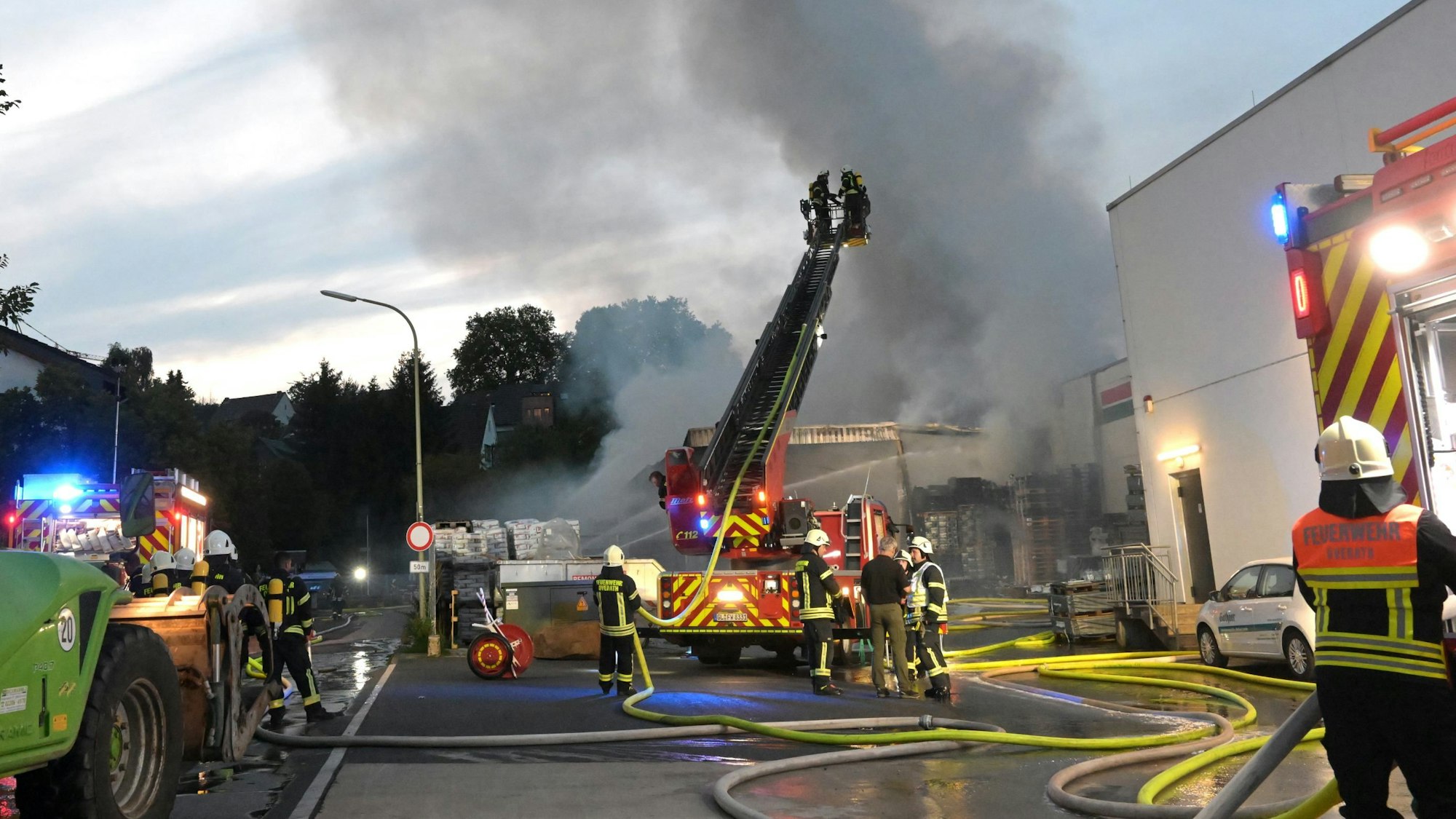 Rauchwolken und Flammen schlagen aus einem Gebäude in den Abendhimmel. Die Feuerwehr löscht den Brand.