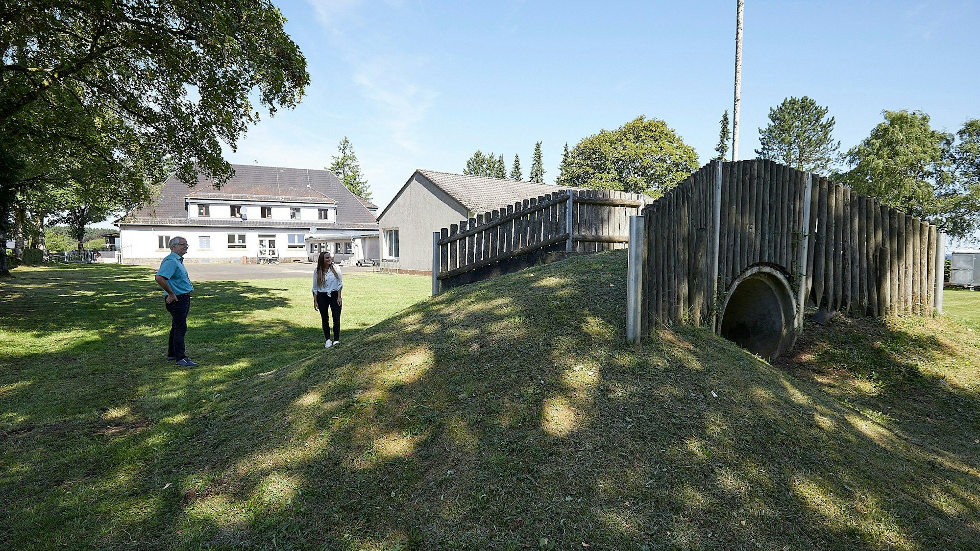 Die neue Leiterin der Kita und ein Verwaltungsmitarbeiter stehen neben einem Kletterhügel.