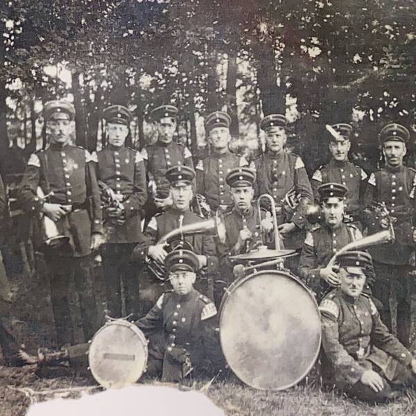 Das historische Bild zeigt eine Blaskapelle mit Instrumenten.