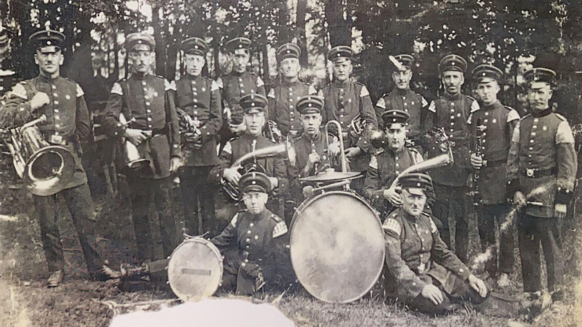 Das historische Bild zeigt eine Blaskapelle mit Instrumenten.
