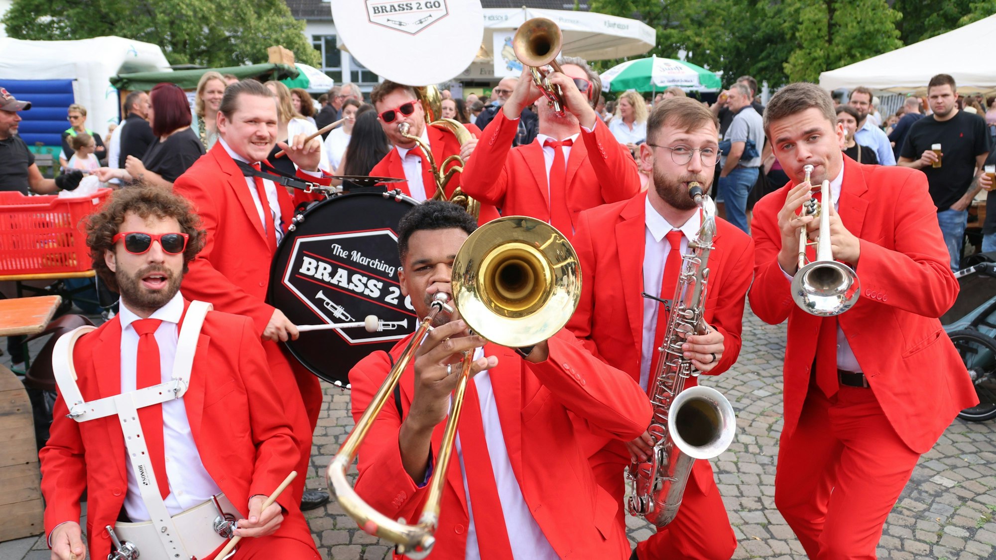 Eine mobile Blaskapelle in roten Anzügen posiert für den Fotografen.