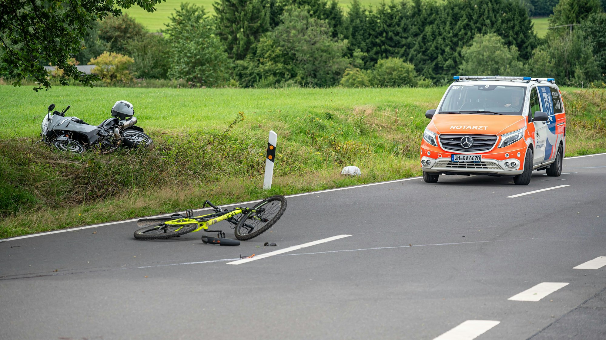 Ein Notarztwagen wartet neben den beiden stark beschädigten Zweirädern.