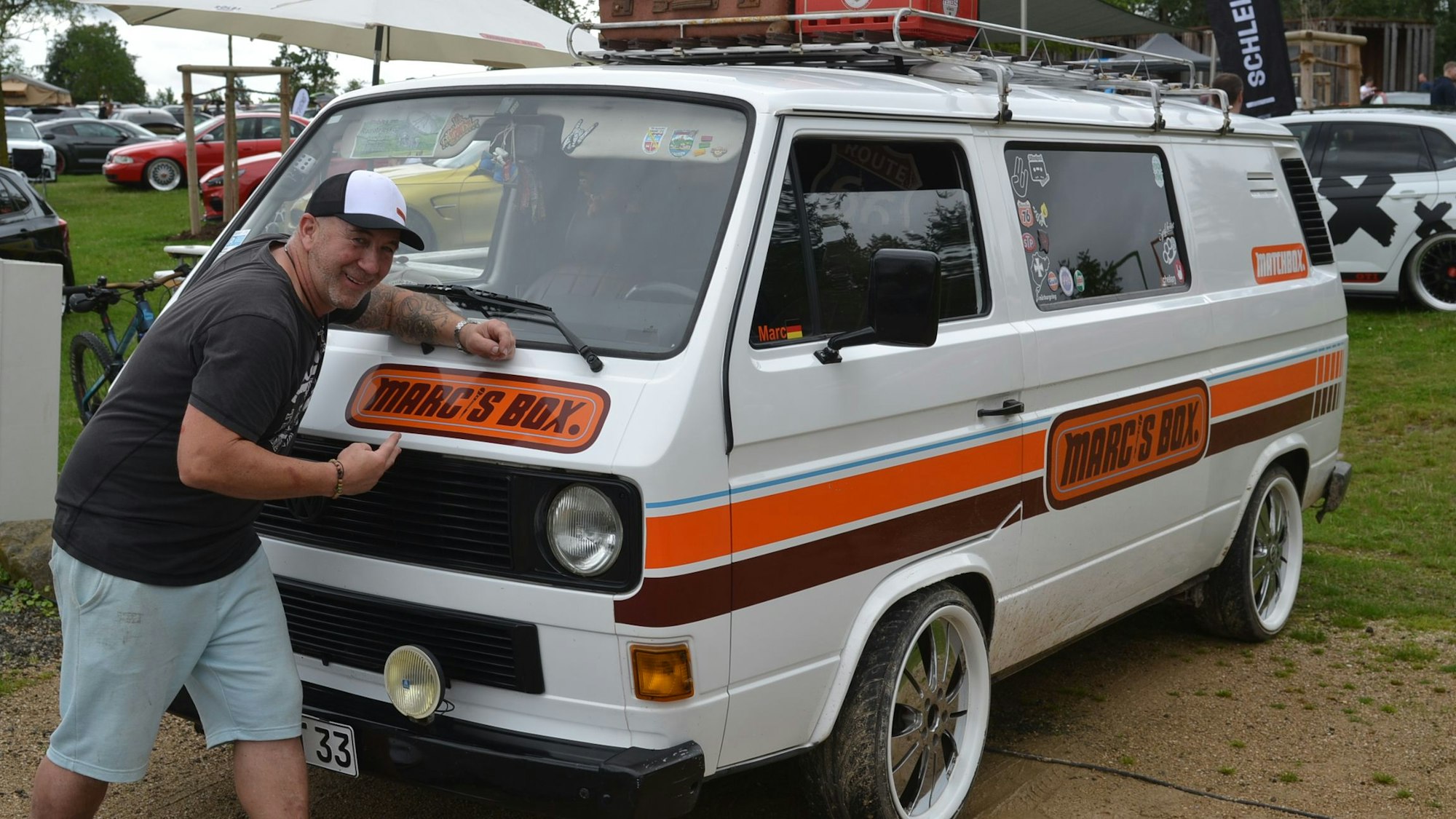 Mark Fühling steht vor seinem VW-Bus mit der Aufschrift "Marc's Box"
