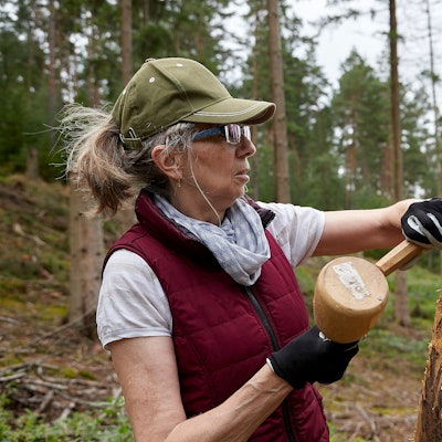 Vera Philipp hält Hammer und Meißel in der Hand und arbeitet an einer Holzfigur, die bereits aussieht wie ein Adler.