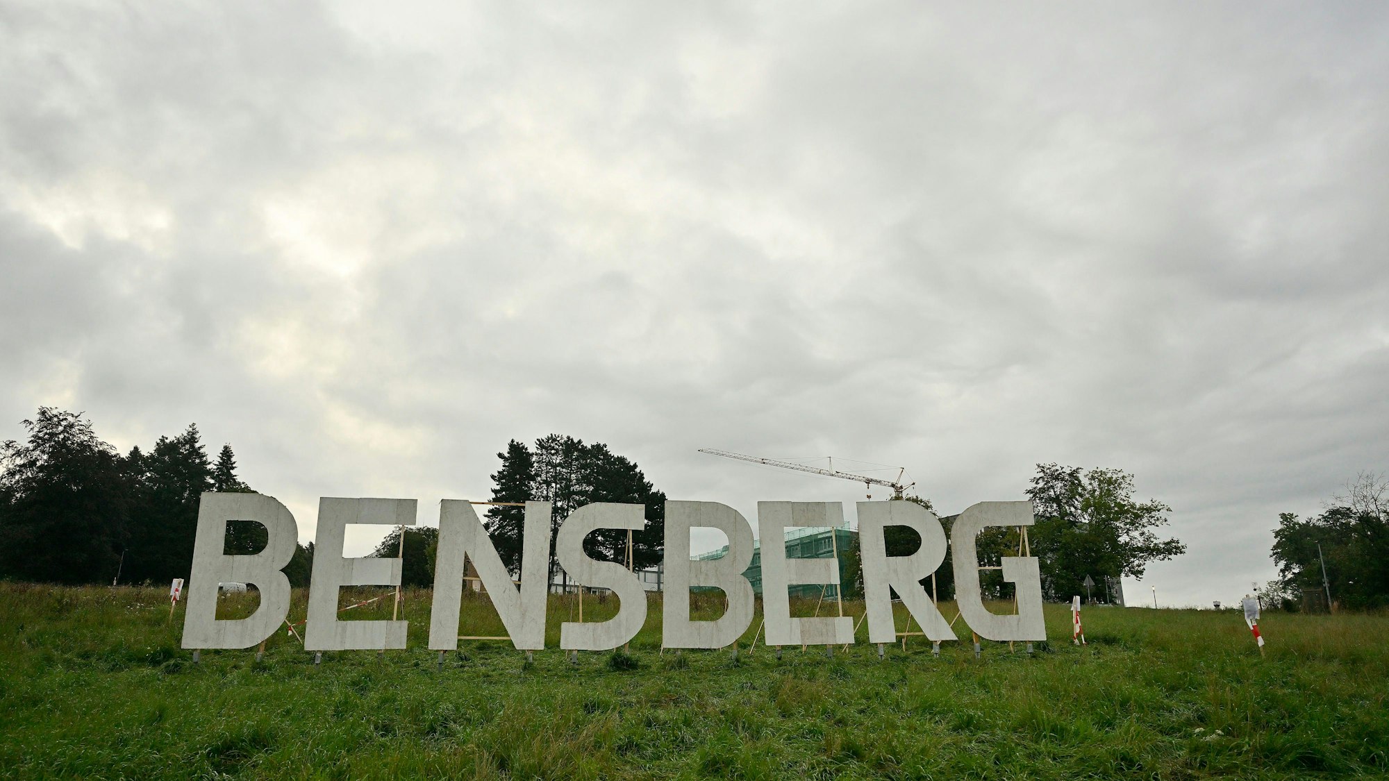 Die riesigen acht Großbuchstaben BENSBERG sind weiß angemalt und stehen auf der Kuppe der Wiese des Stadtgartens unterhalb des Vinzenz-Pallotti-Hospitals.