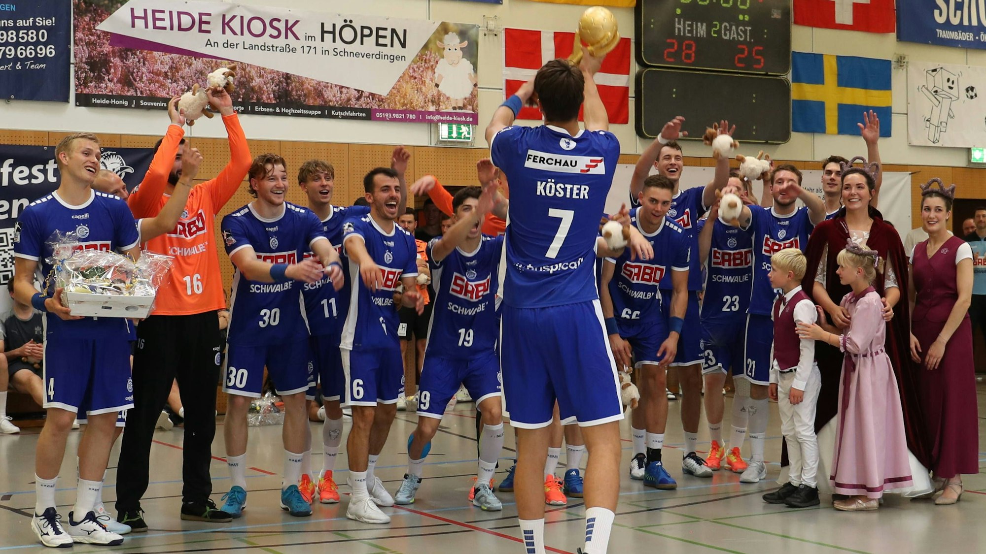 Julian Köster, Kapitän des VfL Gummersbach, reckt den Pokal in Richtung seiner Mitspieler, die jubeln.