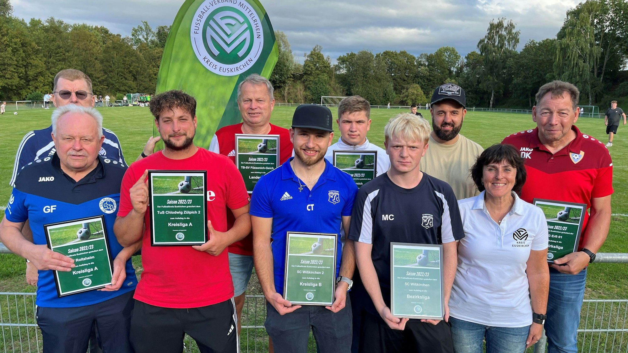 Vertreter der Aufstiegsmannschaften halten Ehrungen in die Kamera.