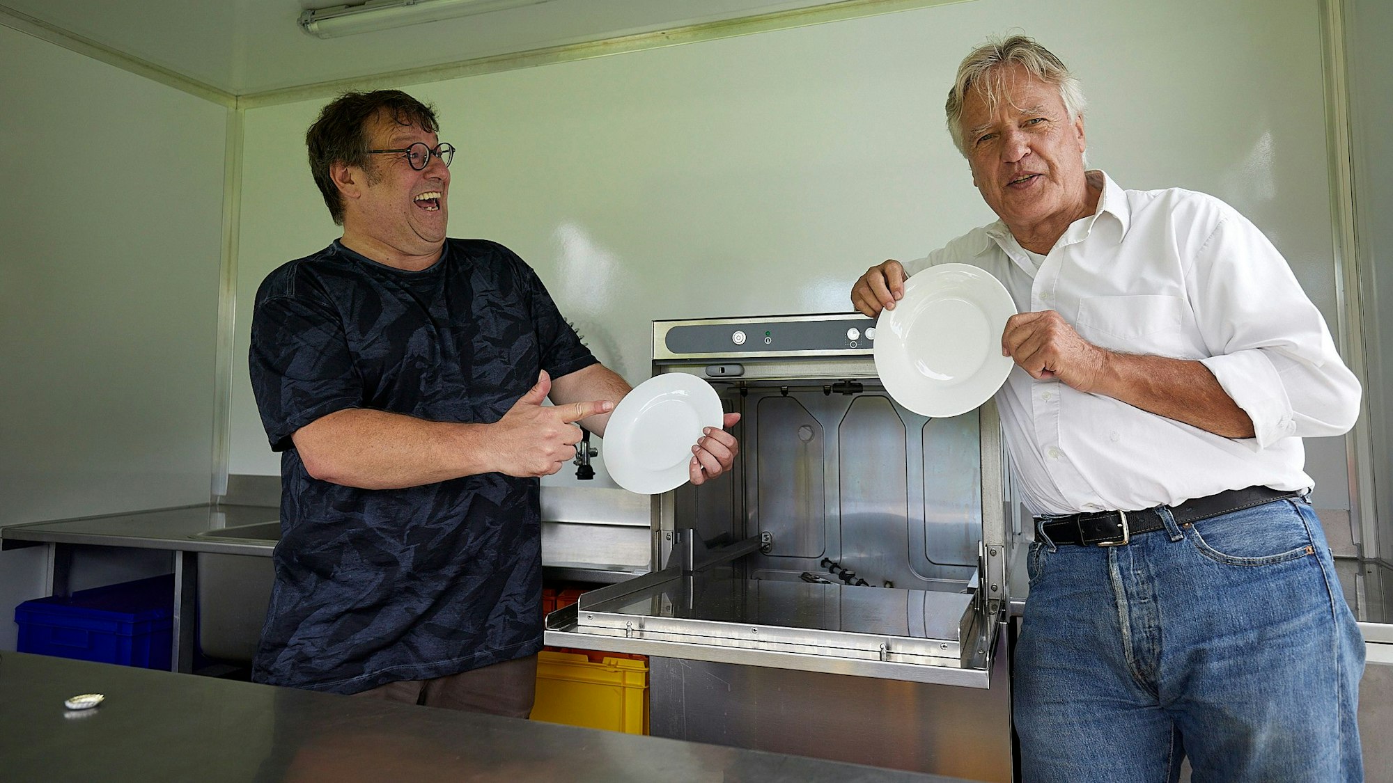 Das Bild zeigt Jo Kaster und Joachim Starke, die Teller in die Kamera halten.