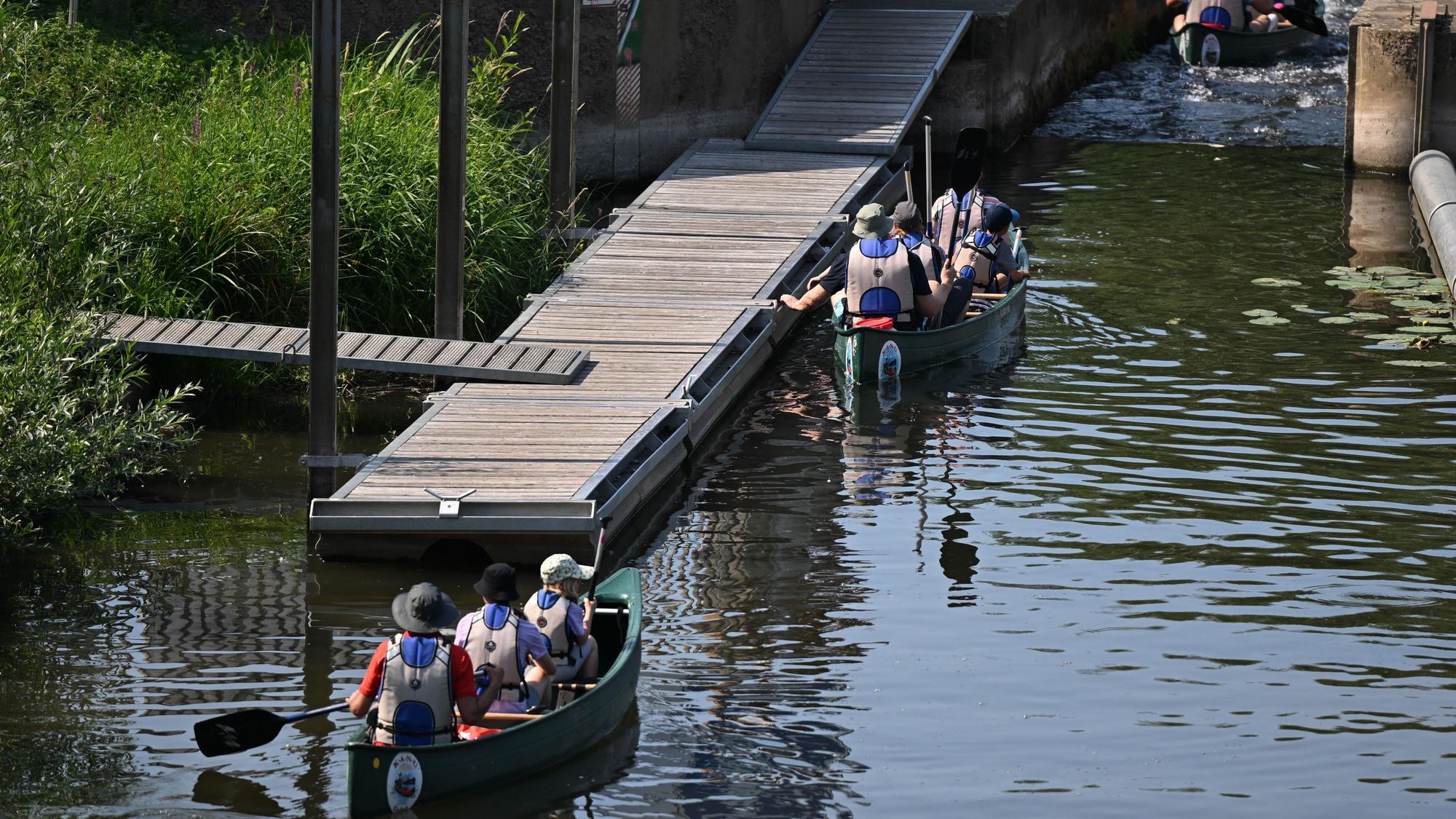 Eine Gruppe steuert bei einem Ausflug auf dem Wasser Kanus durch eine Bootsgasse an einem Wehr der Lahn. +++ dpa-Bildfunk +++