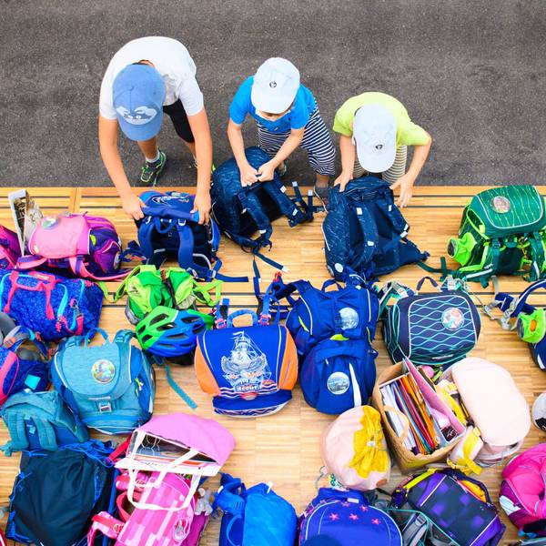 Drei Erstklässler stellen in einer Grundschule ihre Schultaschen ab.