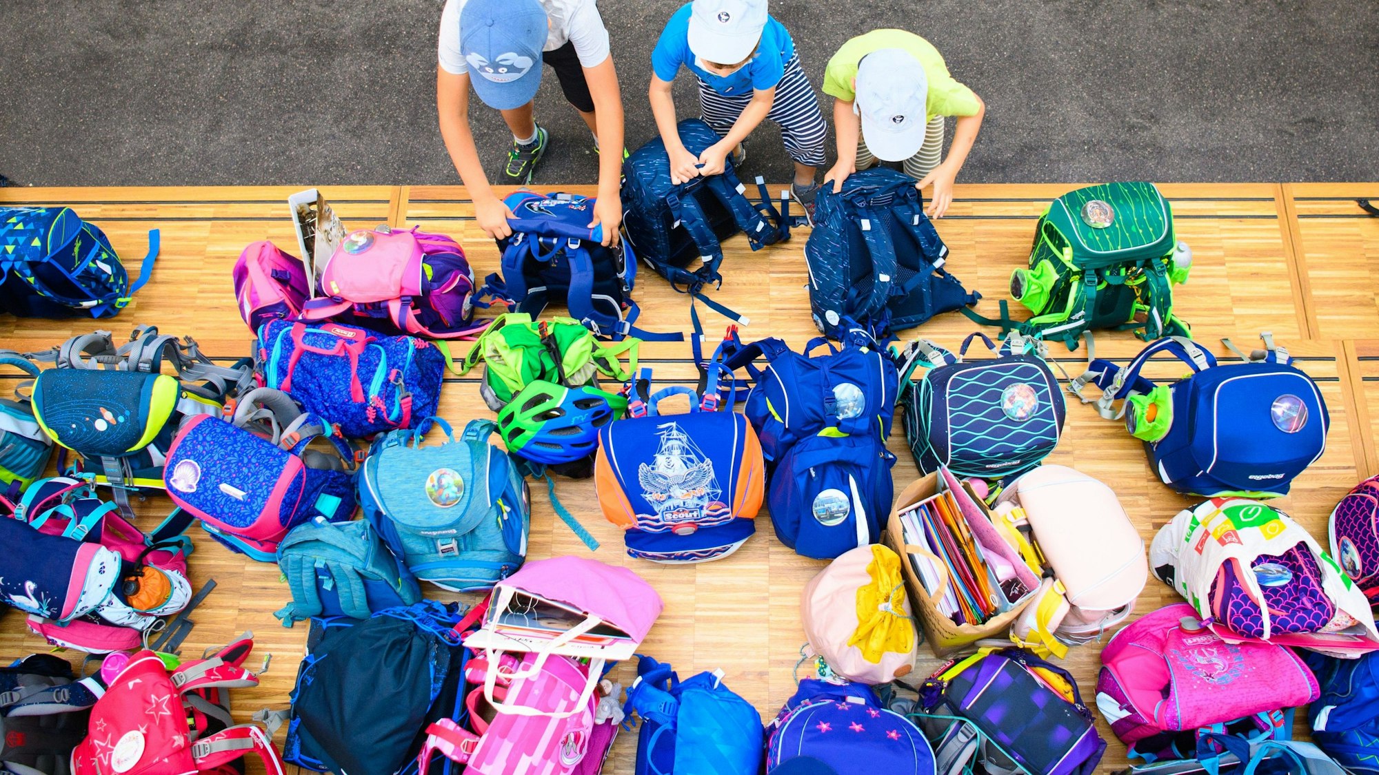 Kinder stehen vor Tornistern.