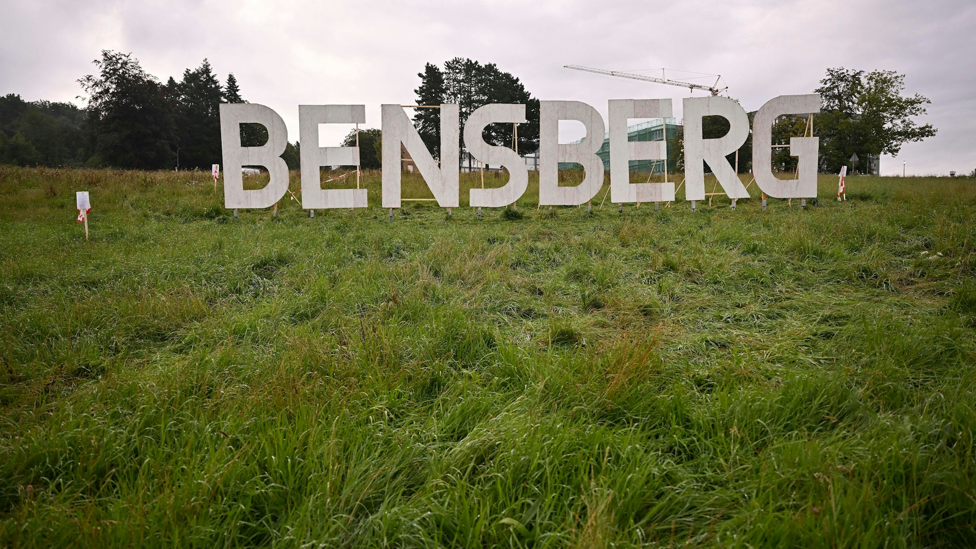 Das Foto zeigt die Kunstinstallation „Bensberg“: Weiße Buchstaben wie die des Hollywood-Schriftzugs auf einer grünen Wiese.