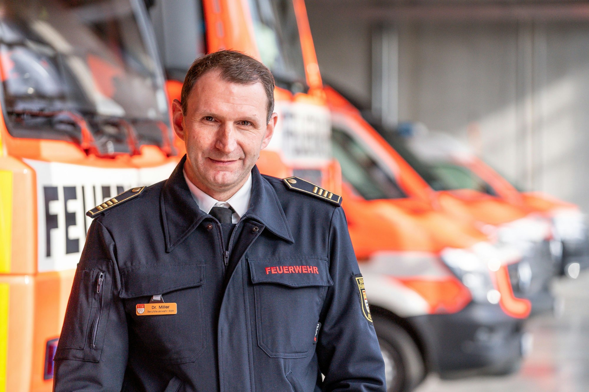 Hofft auf neues Personal: Feuerwehrchef Dr. Christian Miller, der hier in der Wache Kalk vor einer Reihe Einsatzfahrzeugen steht.