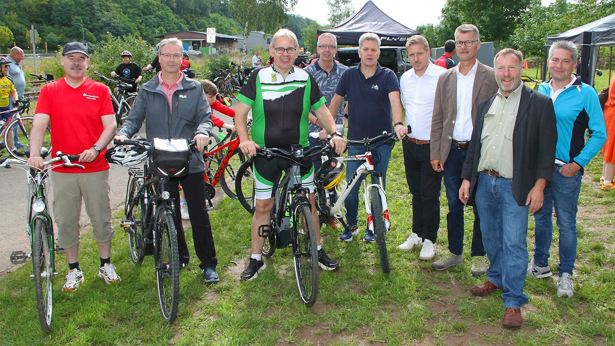 Einige Männer stehen mit ihren Fahrrädern auf einer Wiese.