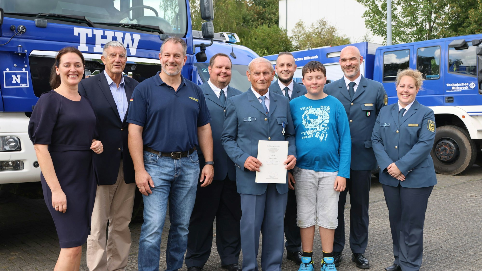 Mehrere Männer und zwei Frauen, darunter Waldbröls Bürgermeisterin Larissa Weber, stehen vor einem THW-Einsatzfahrzeug.