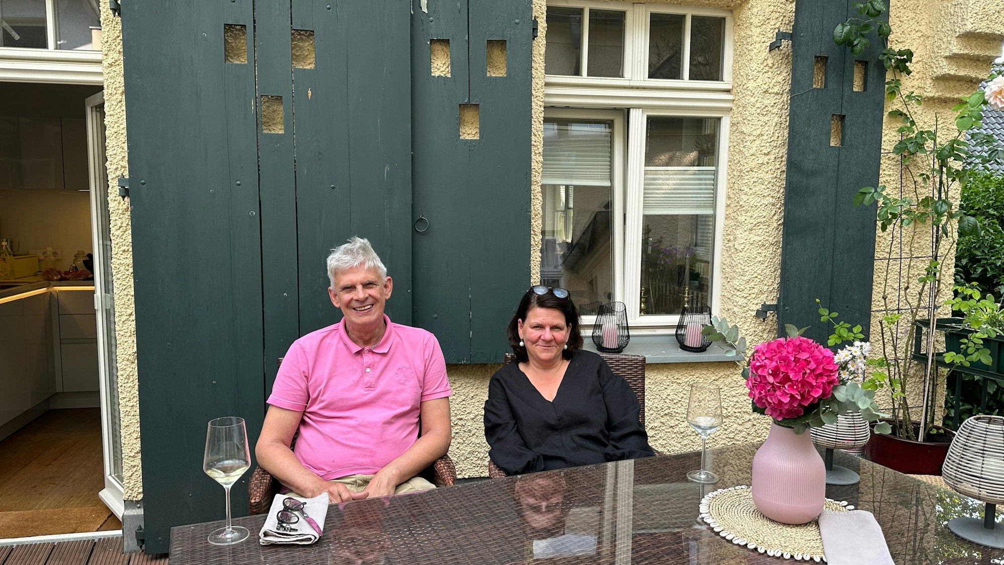 Ein Paar sitzt auf einer Dachterrasse an einem Holztisch.