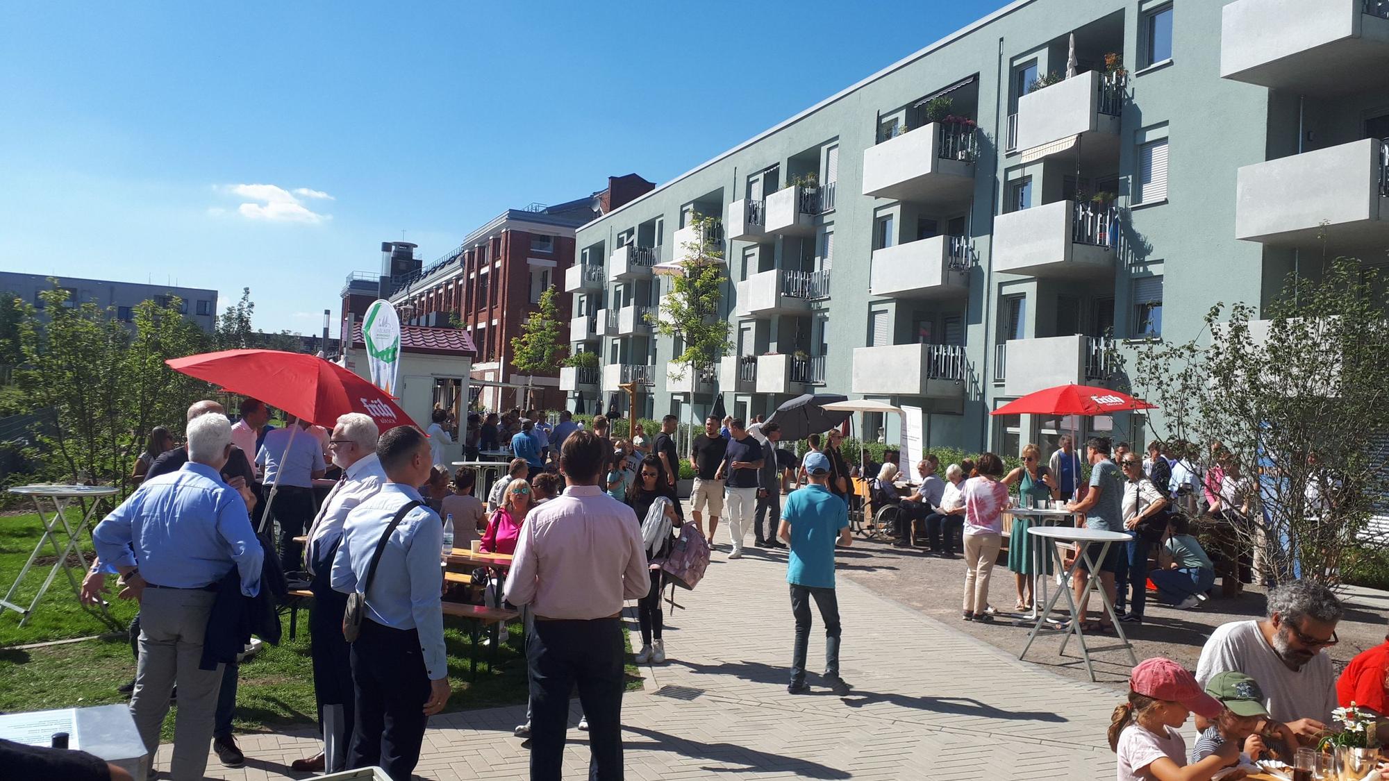 Mehrere Menschen stehen vor dem neuen Wohnhaus an der Ecke Josefine-Clouth-Straße/Xantener Straße.