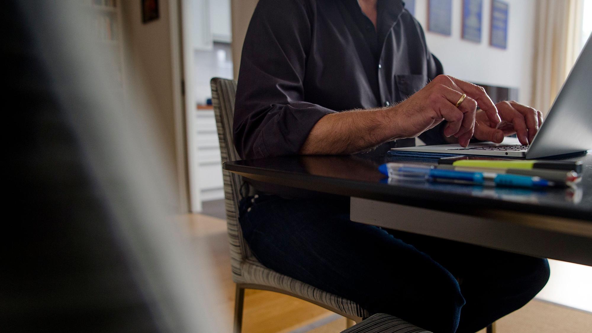 ARCHIV - 01.10.2021, Bayern, München: Ein Mann sitzt zuhause an einem Esstisch und arbeitet an einem Laptop. (Gestellte Szene) Die Zeit, die die Menschen in Deutschland sitzend verbringen, steigt laut einem Report seit Jahren kontinuierlich. (zu dpa «Gesundheitsreport warnt: Deutsche sitzen immer länger») Foto: Finn Winkler/dpa +++ dpa-Bildfunk +++