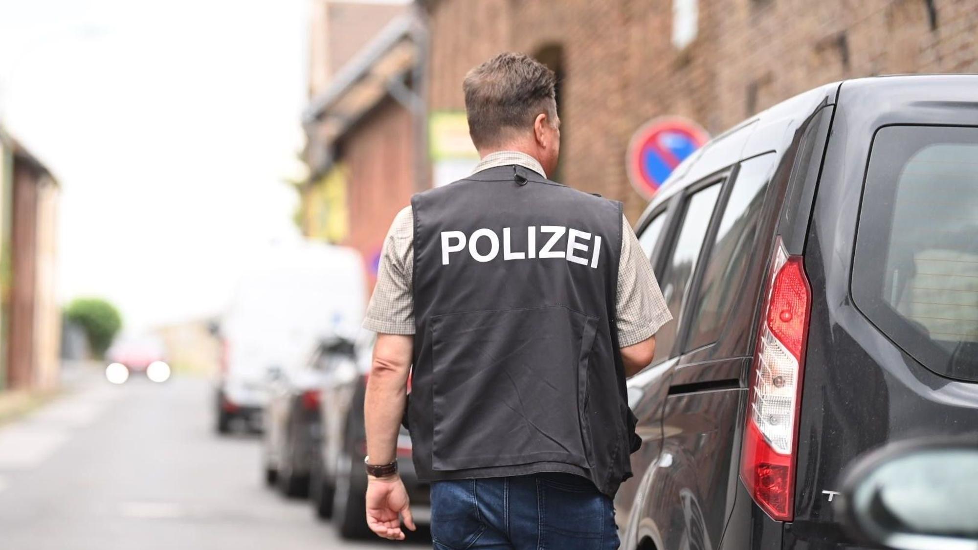 Ein Polizist steht auf einer Dorfstraße neben einem Auto.