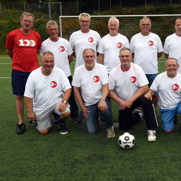Eine Fußballmannschaft, bestehend aus alten Herren, posiert zum Mannschaftsfoto auf einem Rasenplatz.