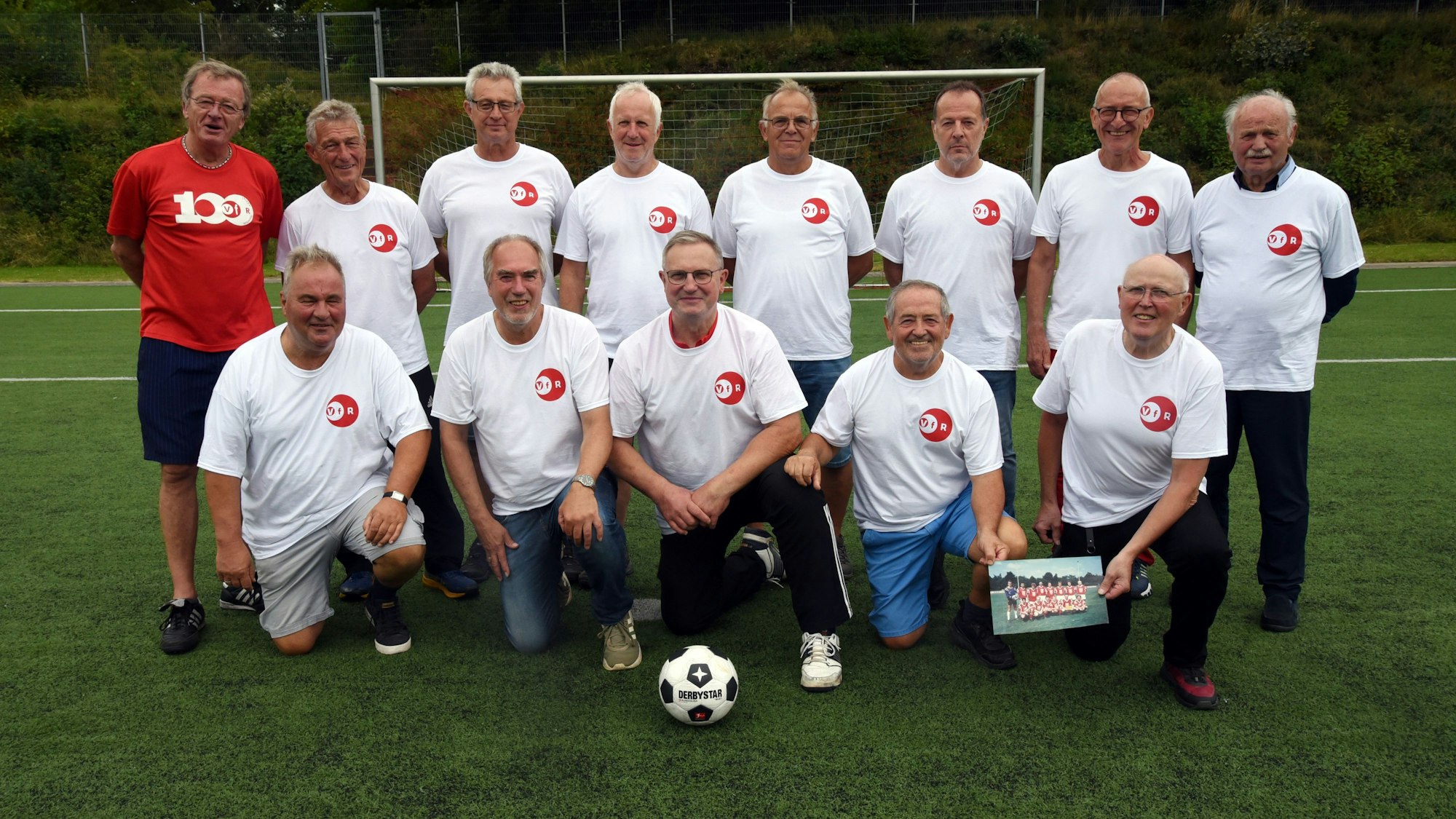 Eine Fußballmannschaft, bestehend aus alten Herren, posiert zum Mannschaftsfoto auf einem Rasenplatz.