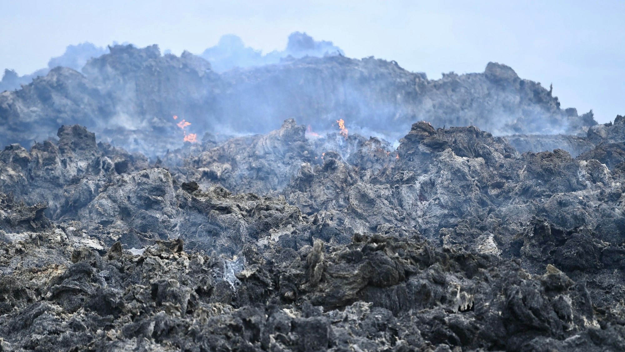 Das Bild zeigt einen Blick auf die Strohmiete. Einzelne Flammen züngeln noch heraus.