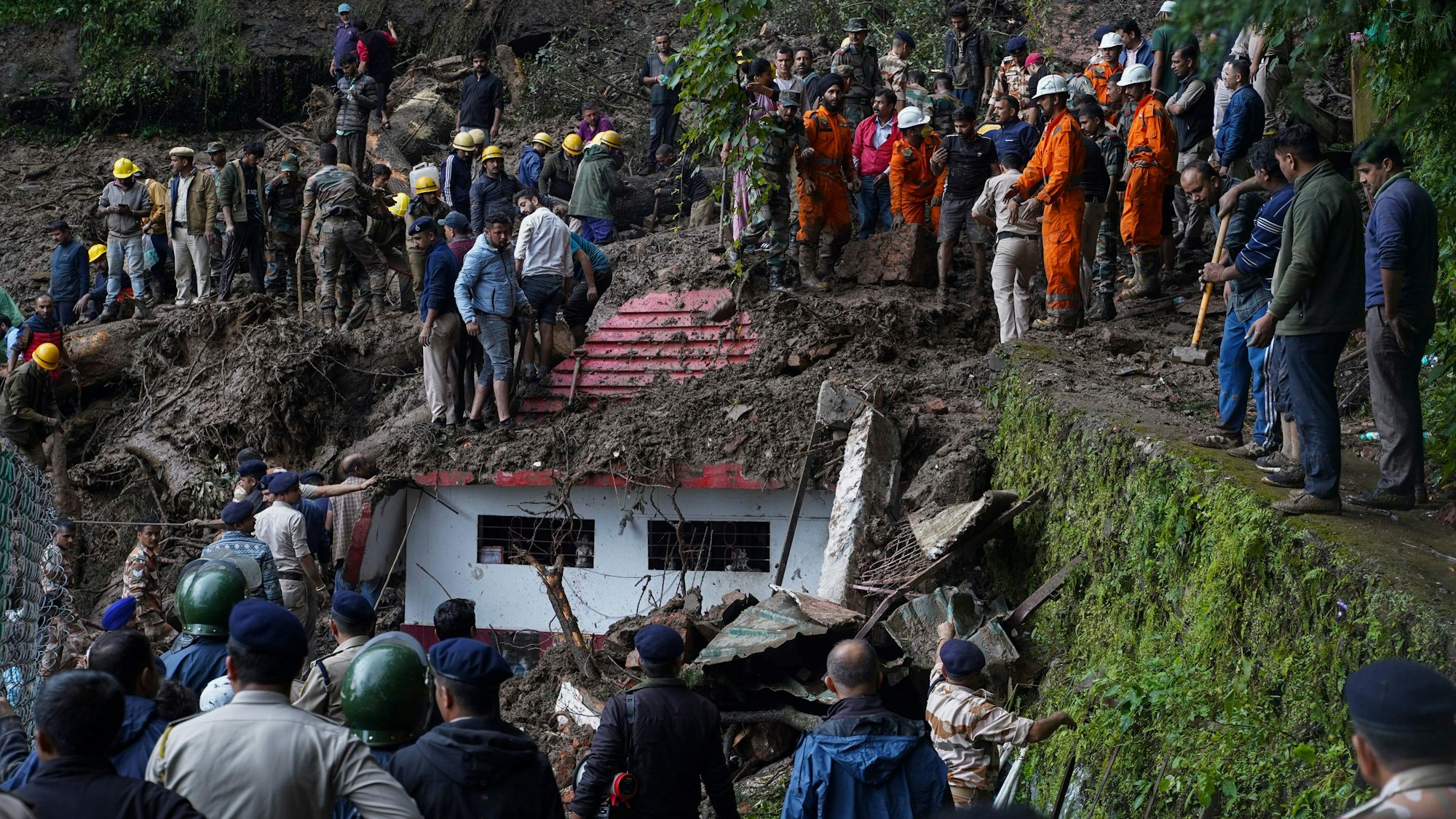 14.08.2023, Indien, Shimla: Rettungskräfte entfernen Schlamm und Trümmer bei der Suche nach Menschen, die nach einem Erdrutsch in der Nähe eines hinduistischen Tempels am Stadtrand verschüttet wurden. Im Zusammenhang mit heftigen Regenfällen der jetzigen Monsunzeit in Indien ist ein Tempel zusammengestürzt. Dabei sollen mindestens neun Menschen getötet worden sein. Foto: Pradeep Kumar/AP/dpa +++ dpa-Bildfunk +++