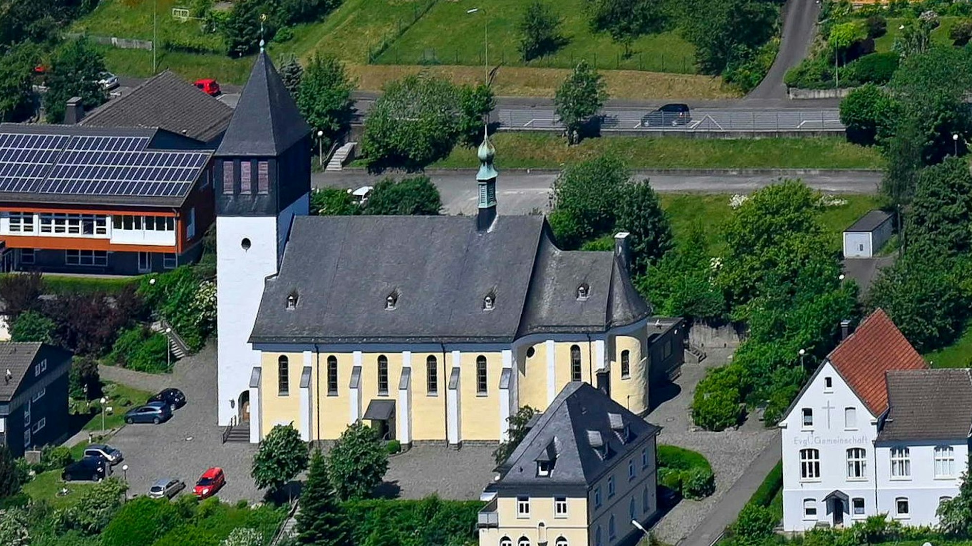 Blick auf eine Kirche, die von einigen Wohnhäusern umringt ist.
