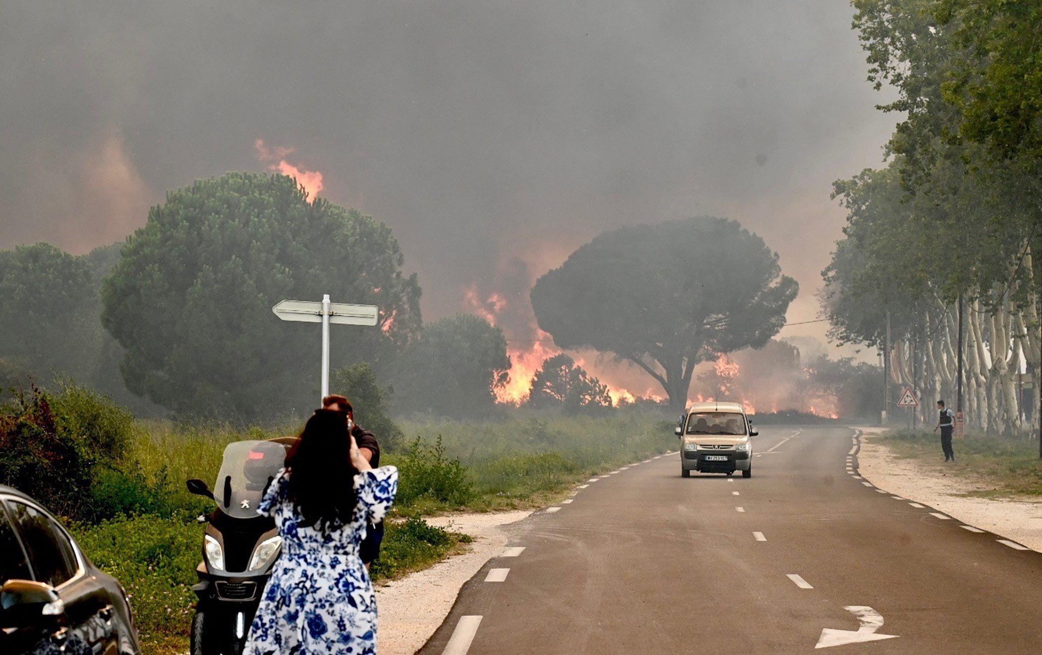 dpatopbilder - 14.08.2023, Frankreich, Argelès-Sur-Mer: Eine Frau fotografiert in Saint-Andre in der Nähe von Argeles-sur-Mer im Südwesten Frankreichs einen Großbrand, der zur Evakuierung  von rund 3000 Touristen von nahegelegenen Campingplätzen geführt hat.