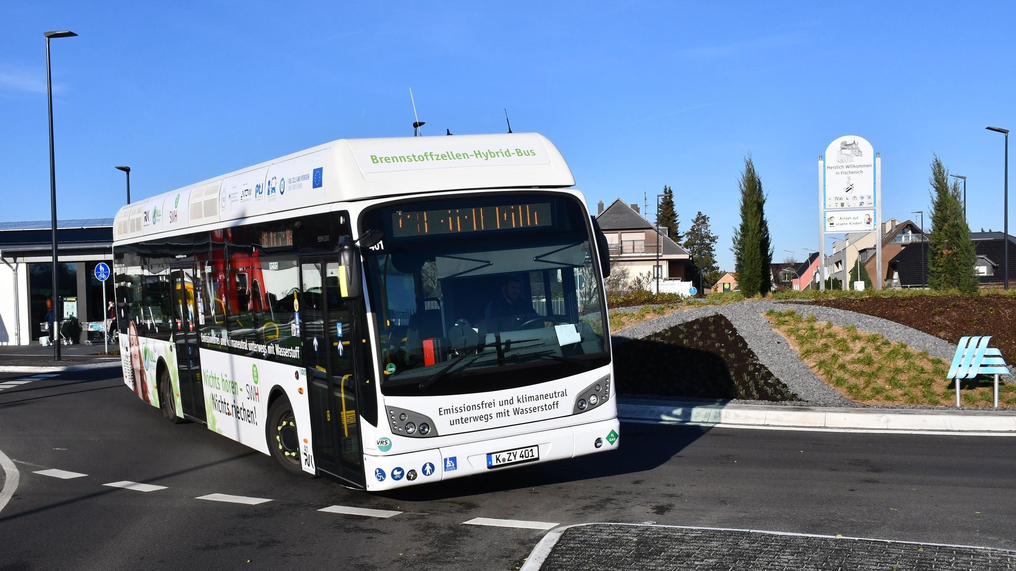 Ein weißer Linienbus fährt in einem Kreisverkehr.