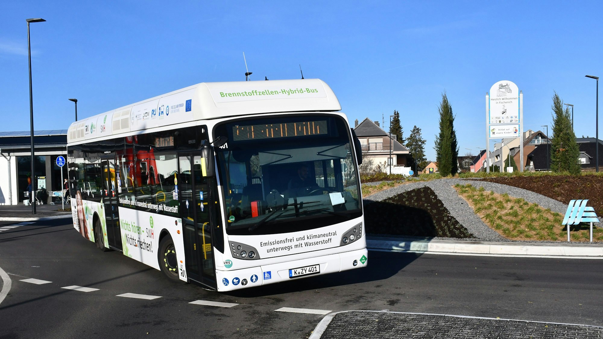 Ein weißer Linienbus fährt in einem Kreisverkehr.