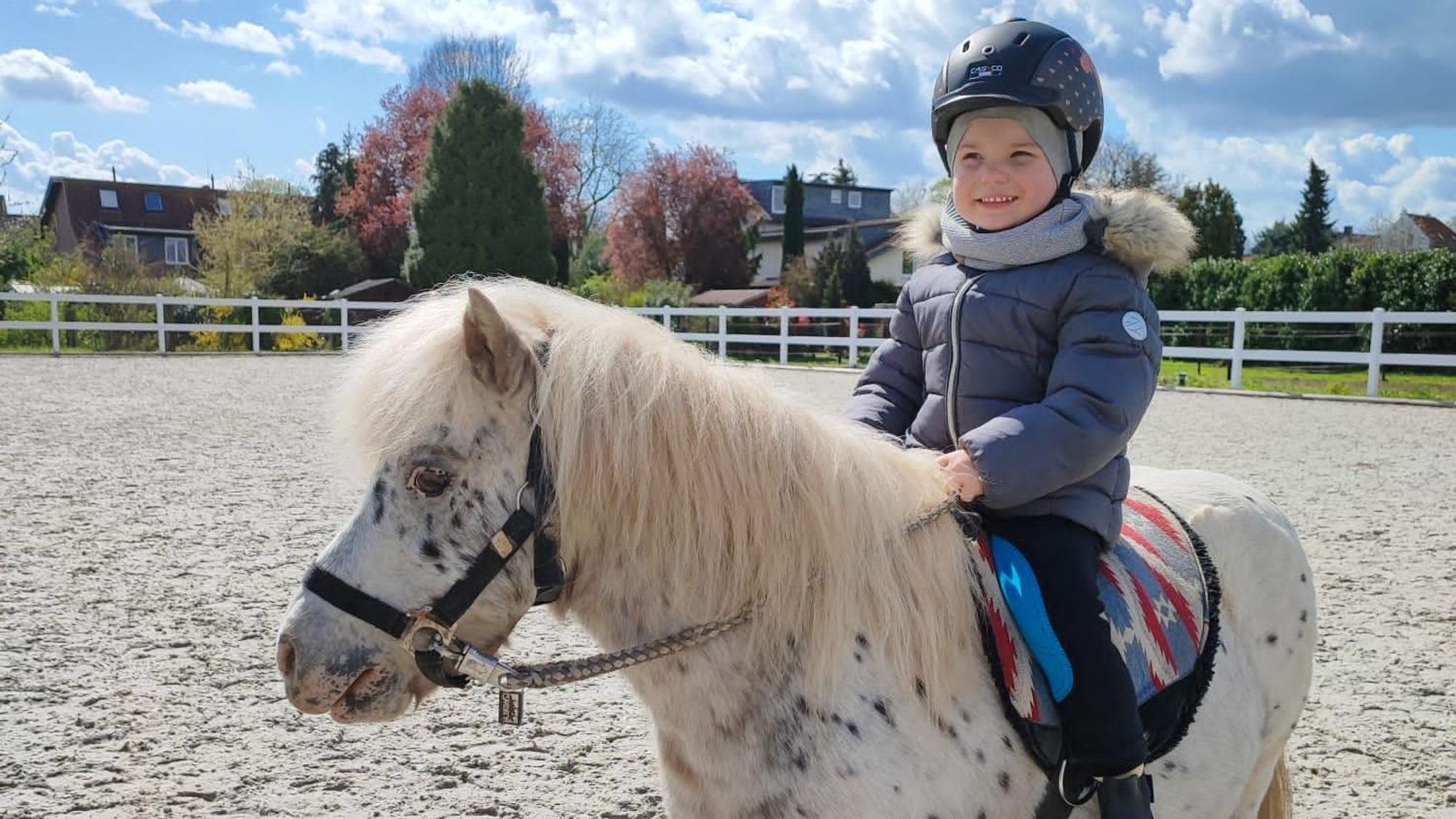 Ein Kind sitzt auf einem Pony.