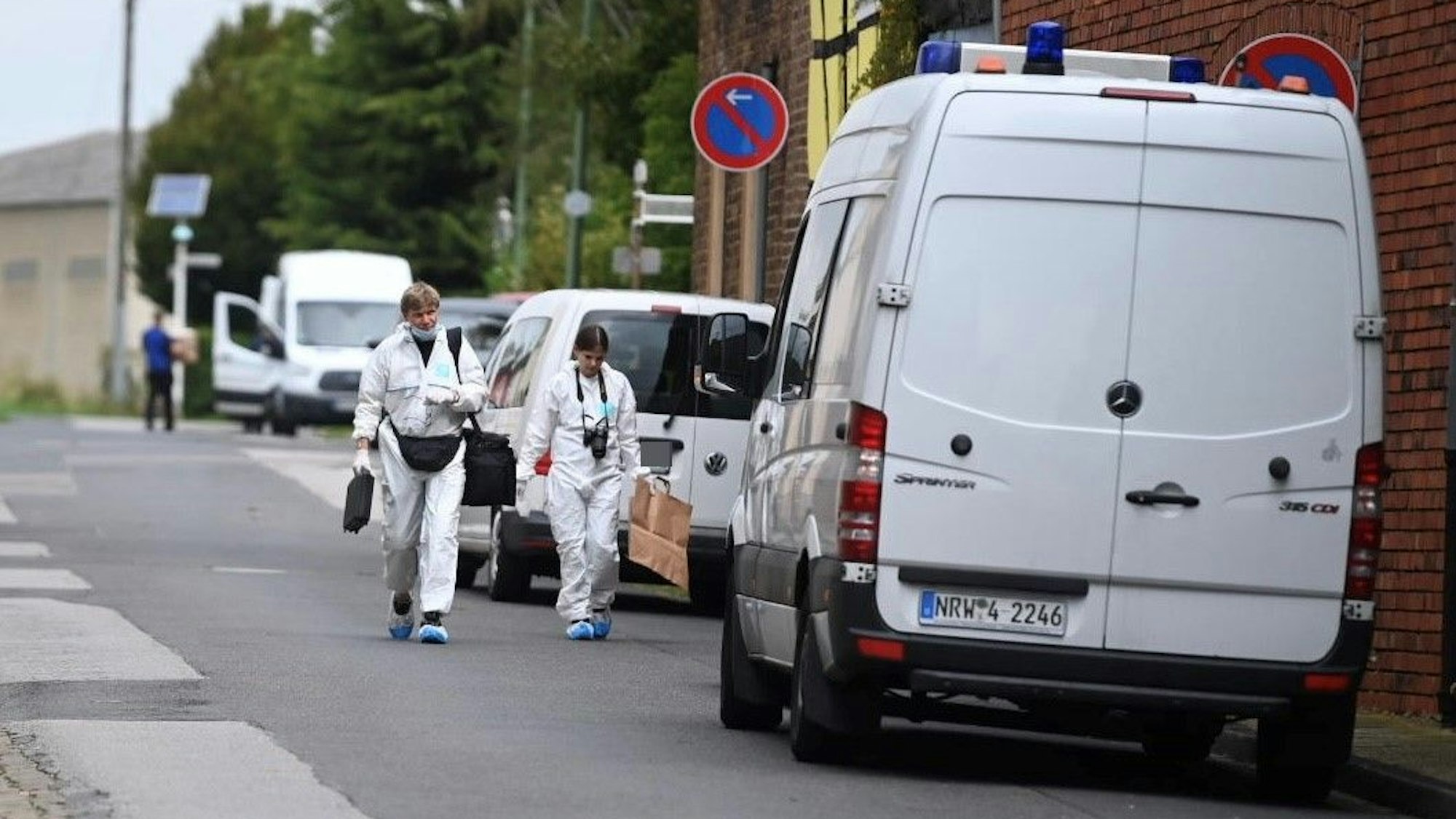 Nach einem Überfall auf ein älteres Ehepaar im Sommer 2023 wurden am Tatort Spuren gesichert. Polizisten in weißen Schutzanzügen gehen über eine Straße.