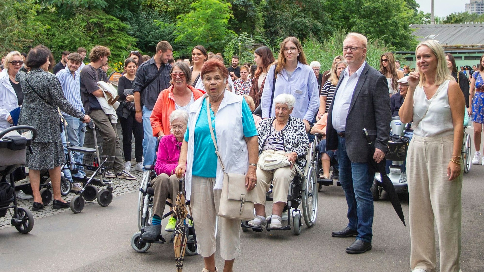Seniorinnen und Senioren gehen mit Azubis durch den Kölner Zoo.