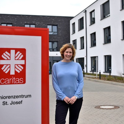 Ein Mann und eine Frau stehen neben dem Schild eines Seniorenheims.