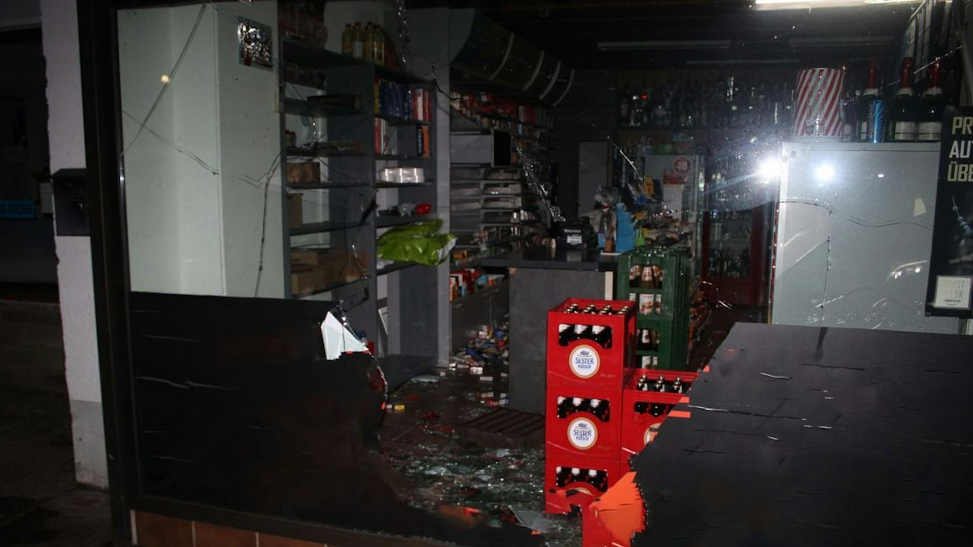 Man sieht eine durchstoßene Scheibe, dahinter ein Verkaufsraum, der durchwühlt wurde.