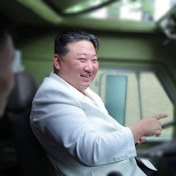 Kim Jong Un sitzt lachend in einem Militärfahrzeug am Steuer.