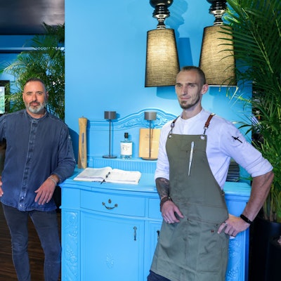 Luis Dias und Küchenchef Cyril Becker stehen in der neu eröffneten Weinbar vor einer türkisfarbigen Kommode.